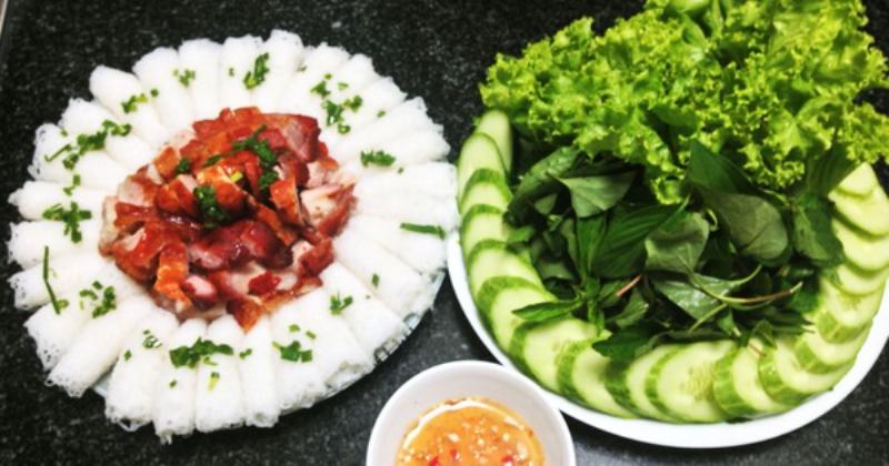 Đĩa thịt heo quay được ăn kèm với rau sống và nước chấm.